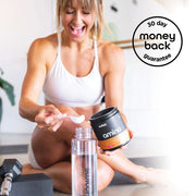 Happy woman in a gym setting scooping amino powder into a water bottle, with a container labeled 'Switch amino' in her hand, and a '30 day money back guarantee' badge in the corner.