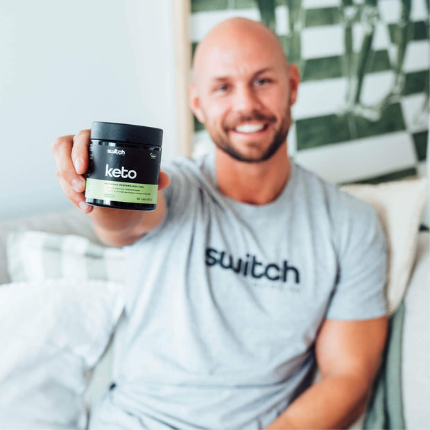 Happy man showcasing Switch Nutrition Keto supplement, a vegan ketogenic performance fuel in a compact container.