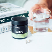 "Keto" supplement container beside a glass of water and green apples: "Switch Nutrition Keto supplement by a refreshing glass of water and healthy green apples, emphasising the product's health benefits.