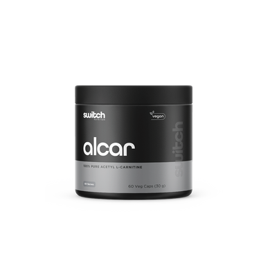 A container of 'alcar 100% pure acetyl L-carnitine' by Switch Nutrition, labeled as vegan, with 60 vegetable capsules (30 grams) and two visible capsules in front of the container.