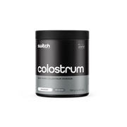 A container of Switch Nutrition's Colostrum, labeled as 100% pure colostrum powder from grass-fed sources. The packaging is black with white and grey text, indicating it's unflavoured with 150 servings in a 150g container.