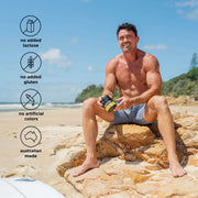 Man sitting on the beach holding a container of Switch Nutrition Hydrate, with icons for no lactose, gluten, artificial colors, and Australian made.