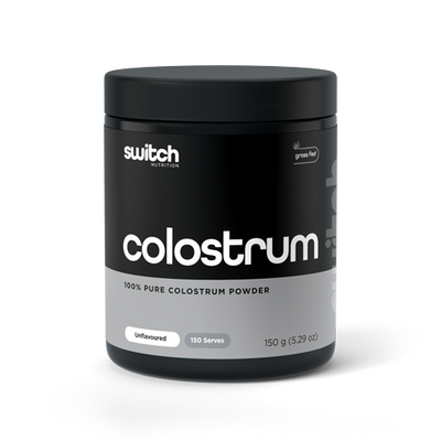 A container of Switch Nutrition's Colostrum, labeled as 100% pure colostrum powder from grass-fed sources. The packaging is black with white and grey text, indicating it's unflavoured with 150 servings in a 150g container.