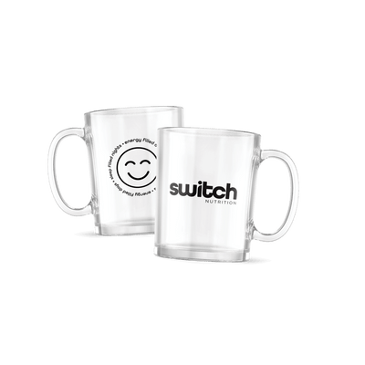 Two clear glass mugs from Switch Nutrition. One mug features the "Switch Nutrition" logo in black, while the other displays a smiling face graphic surrounded by the text "Energy Filled Days • Sleep Filled Nights" in a circular design. Each mug has a sturdy handle and a sleek, modern design.